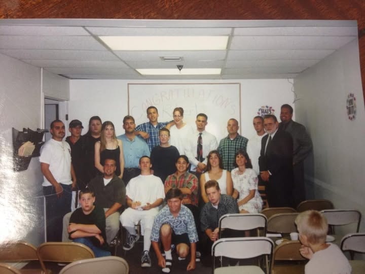 Class of 1997 group photo with graduates and staff in front of Congratulations banner