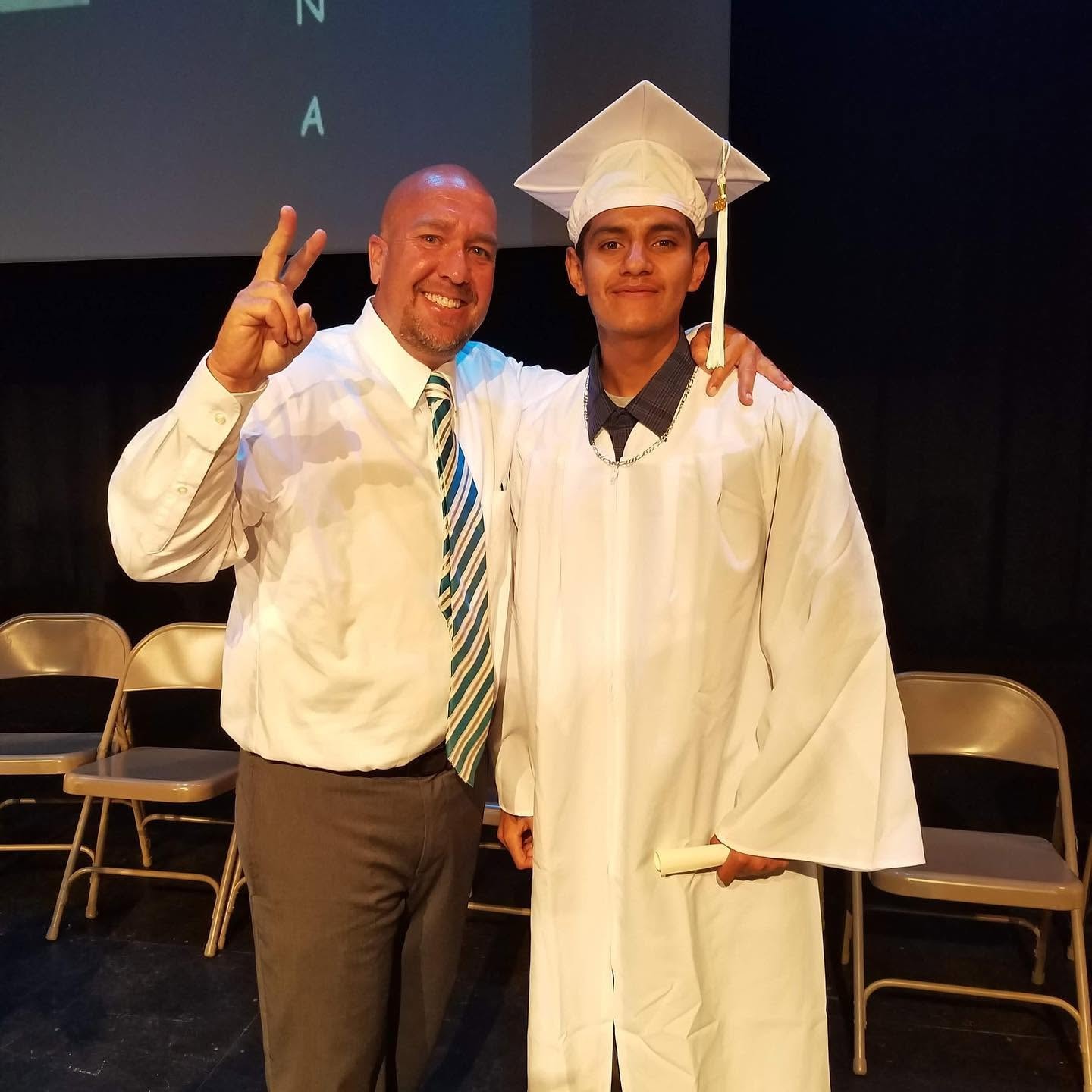 Coach and Class of 2019 graduate holding diploma on stage at Operation New Hope ceremony