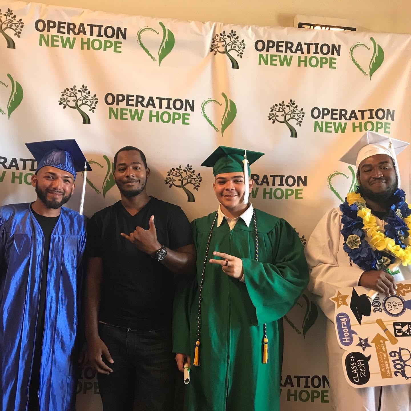 Four Class of 2019 graduates in front of Operation New Hope step-and-repeat backdrop