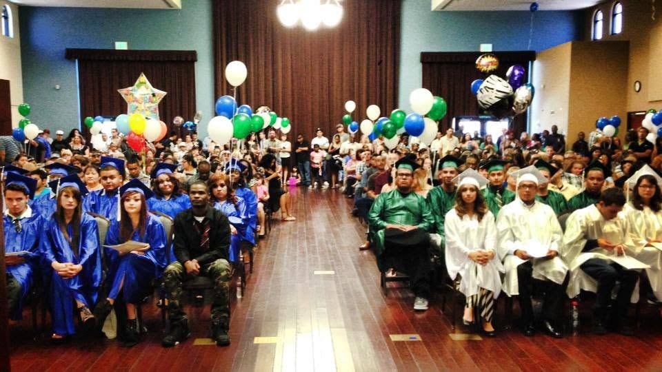 Class of 2016 graduation ceremony in decorated hall with blue, green, and white robes