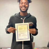 Graduate smiling and holding certificate at Operation New Hope