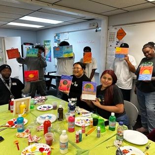 Students holding up artwork in class workshop