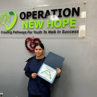 Student holding CNA certificate at Operation New Hope